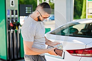 Young man waiting for petrol station operator to pay for fuel.