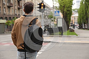 Young man waiting for traffic lights to cross street
