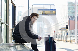 Young man waiting for train with suitcase travel bag