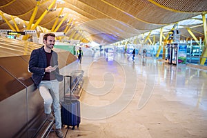 Young man waiting and using mobile phone at the airport