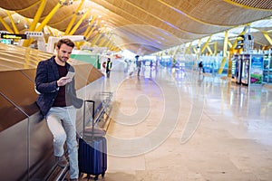 Young man waiting and using mobile phone at the airport