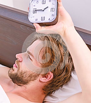 A young man waking up in bed and stretching his arms. Guy is lying in the bed. Man morning.