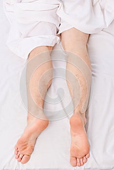 A young man waking up in bed and stretching his arms. Guy is lying in the bed. Morning on bed.