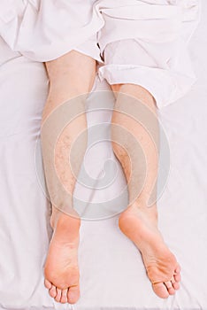 A young man waking up in bed and stretching his arms. Guy is lying in the bed. Morning on bed.