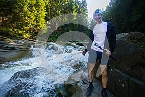 Young man walk near fast river in forest