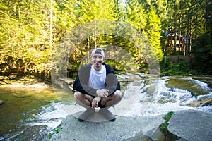 Young man walk near fast river in forest