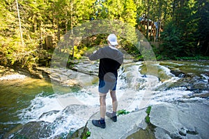 Young man walk near fast river in forest