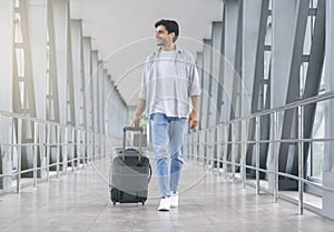 Young man walking in airport walkway with luggage