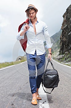 Young man walking with bag on the road
