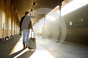 Young man walking with bag at train station