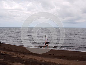 Young man walking barefoot aimlessly along a sandy seashore