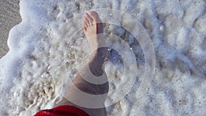 Young man walking barefoot on the beach