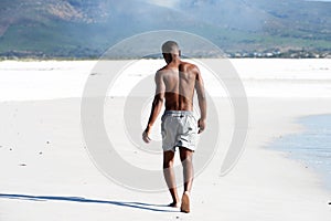 Young man walking barefoot on beach