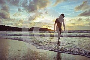 Young man walking on beach when sunset