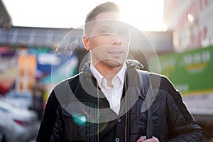 Young man walking in city during day, lensflare effect. photo