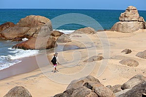 Young man walking down a lonely beach lined with rocks and ocean