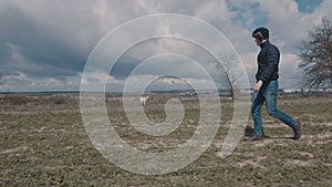 Young man walking with his yellow labrador across the field