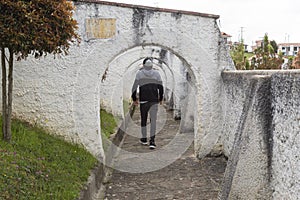 A young man walking inside an old arc colonial peatonal street at South American town photo