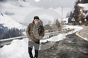 Young man walking on roadside under the snow