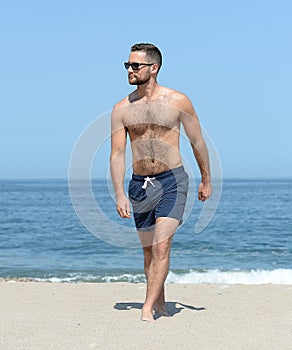 Young man walking on sandy beach