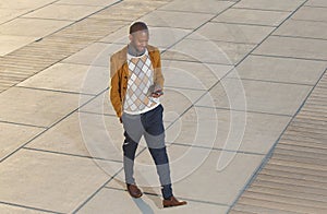 Young man walking and sending message on mobile phone