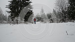 Young man walking on snow covered trail in forest