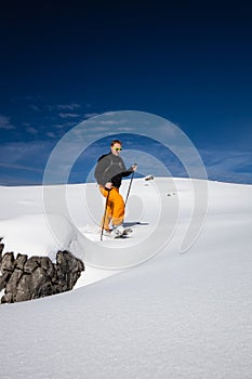 Young man walking with snowshoes uphill in high mountains