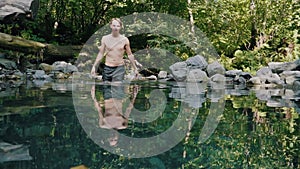 Young man walking in stones and jump into refreshing cool water of mountain forest lake. Concept staycation adventures