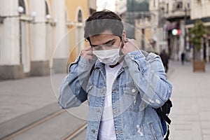 Young man is walking on the street with a protective mask