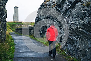 Young man walking towards Wicklow Head Lighthouse in Ireland