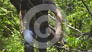Young man walking in tropical forest. Traveling man going through dense rainforest thickets. Tourism and travel.
