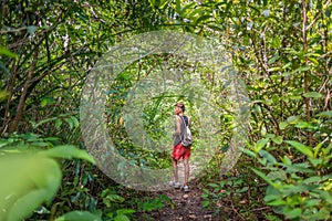 Young man walks along the path through bush and tree thickets