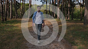 A young man walks in a picturesque pine forest