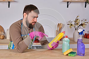 Young man wanted to help his wife in housecleaning, but he doesn`t know what to do with all of detergents