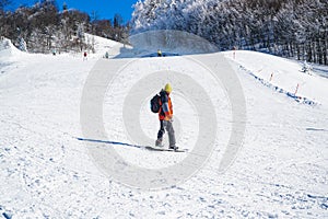Young man in warm clothes snowboarding freestyle downhill. Winter tourism in mountains