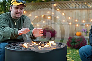 Young man warming his hands over a backyard fire