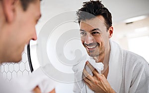 Young man washing face in the bathroom in the morning, daily routine.