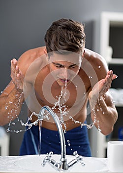 Young man washing face after shaving