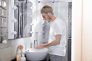 Young man washing hands in bathroom