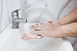Young man washing hands over sink in bathroom, closeup, Corona virus or Covid-19 prevention, hygiene to stop.