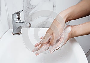 Young man washing hands over sink in bathroom, closeup, Corona virus or Covid-19 prevention, hygiene to stop.