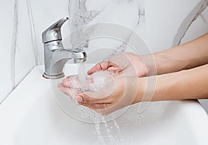 Young man washing hands over sink in bathroom, closeup, Corona virus or Covid-19 prevention, hygiene to stop.