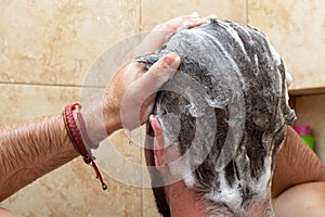 young man washing head hair with shampoo in the shower, male personal hygiene bathroom routine, self skin care, scalp treatment