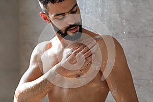 Young man washing his body with soap foam