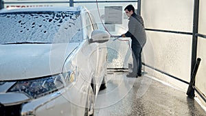 Young man washing his dirty car at self service carwash. Automobile care, transport cleaning, dirty car.