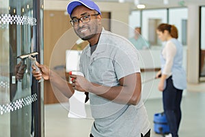 young man washing window in office