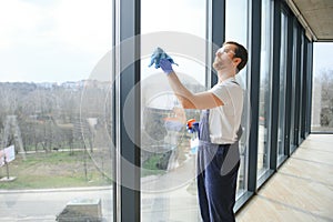 Young man washing window in office