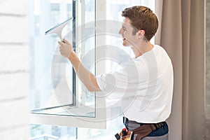 Young man washing window in office