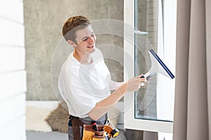 Young man washing window in office