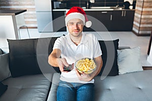 Young man watch tv in his own apartment. Happy guy celebrating new year or christmas period. Holidays time alone in room